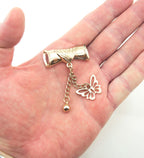 Close-up of the gold tone scroll and butterfly pendant showing intricate design.