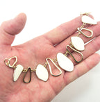 Close-up of the gold tone and white enamel pendant chain highlighting its details.