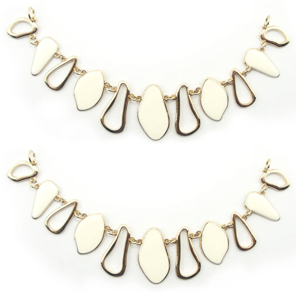 Gold tone and white enamel pendant chain displayed on a flat surface.