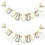 Gold tone and white enamel pendant chain displayed on a flat surface.