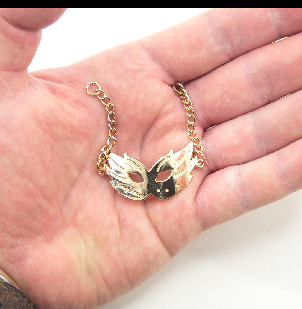 Three gold tone metal party mask pendants displayed together.