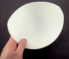 Close-up of soft 6XL white bra pads showing their curved shape.