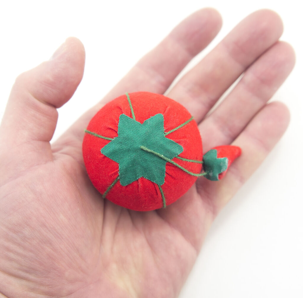 Emery used for sharpening pins next to a tomato pin cushion.
