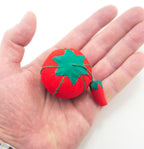 Tomato pin cushions arranged neatly in a sewing basket.