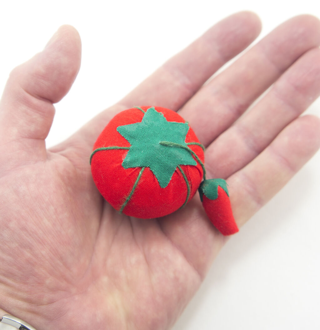 Tomato pin cushions arranged neatly in a sewing basket.