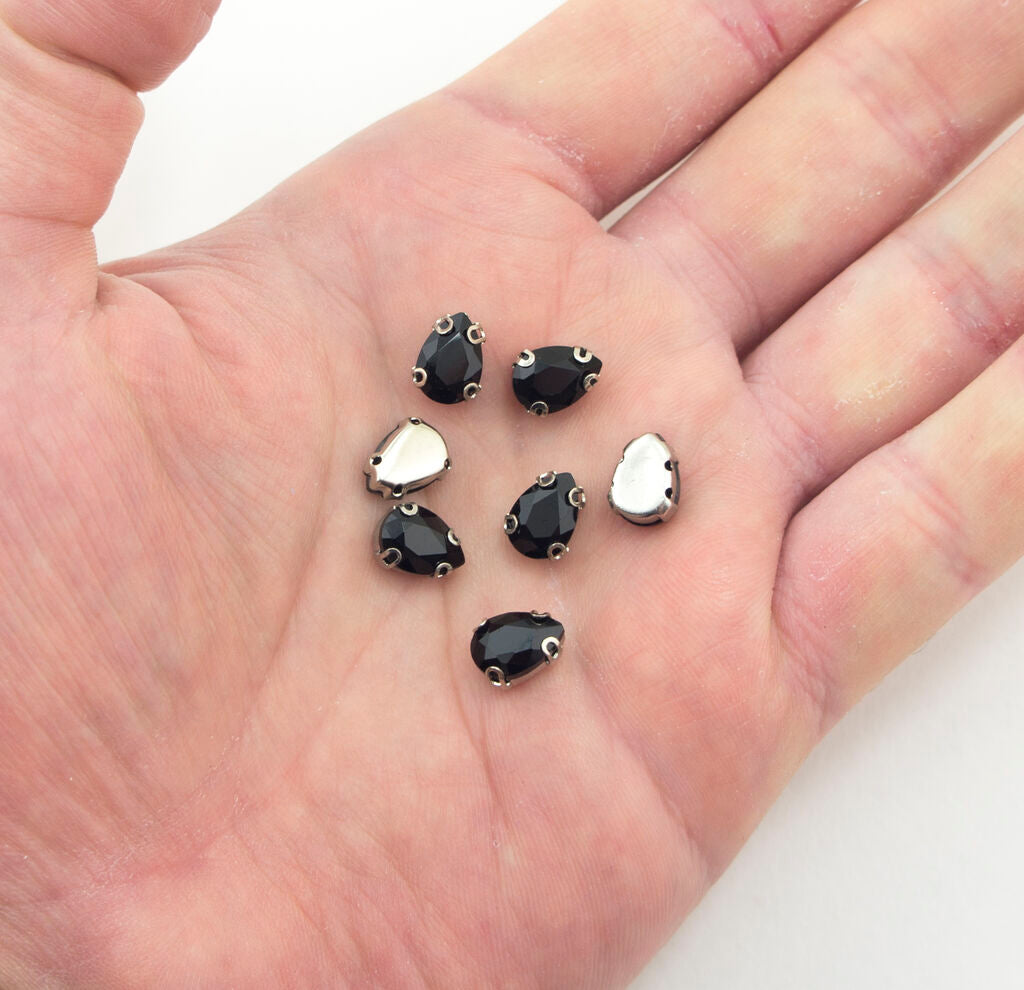 Close-up of a black teardrop glass crystal trim with silver tone metal mount.