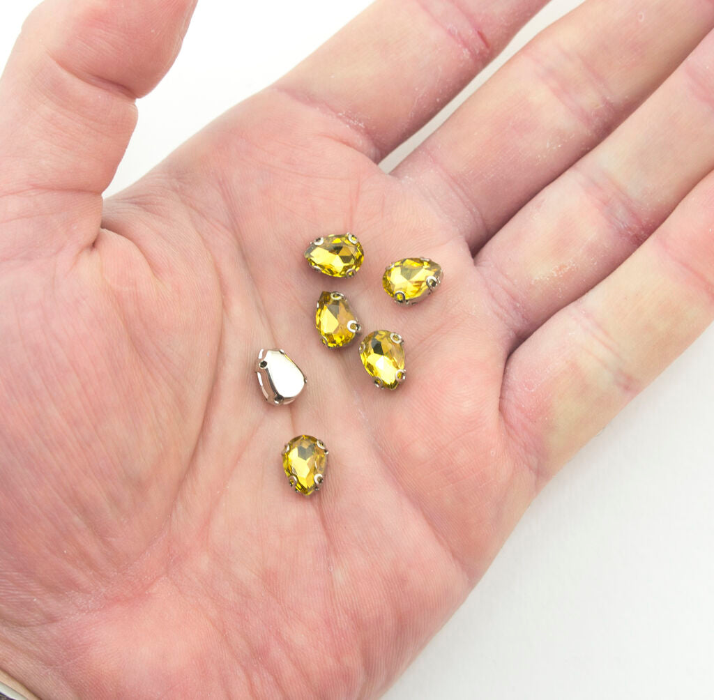 Close-up of a golden yellow teardrop glass crystal trim with silver tone metal mount.
