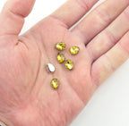 Close-up of a golden yellow teardrop glass crystal trim with silver tone metal mount.