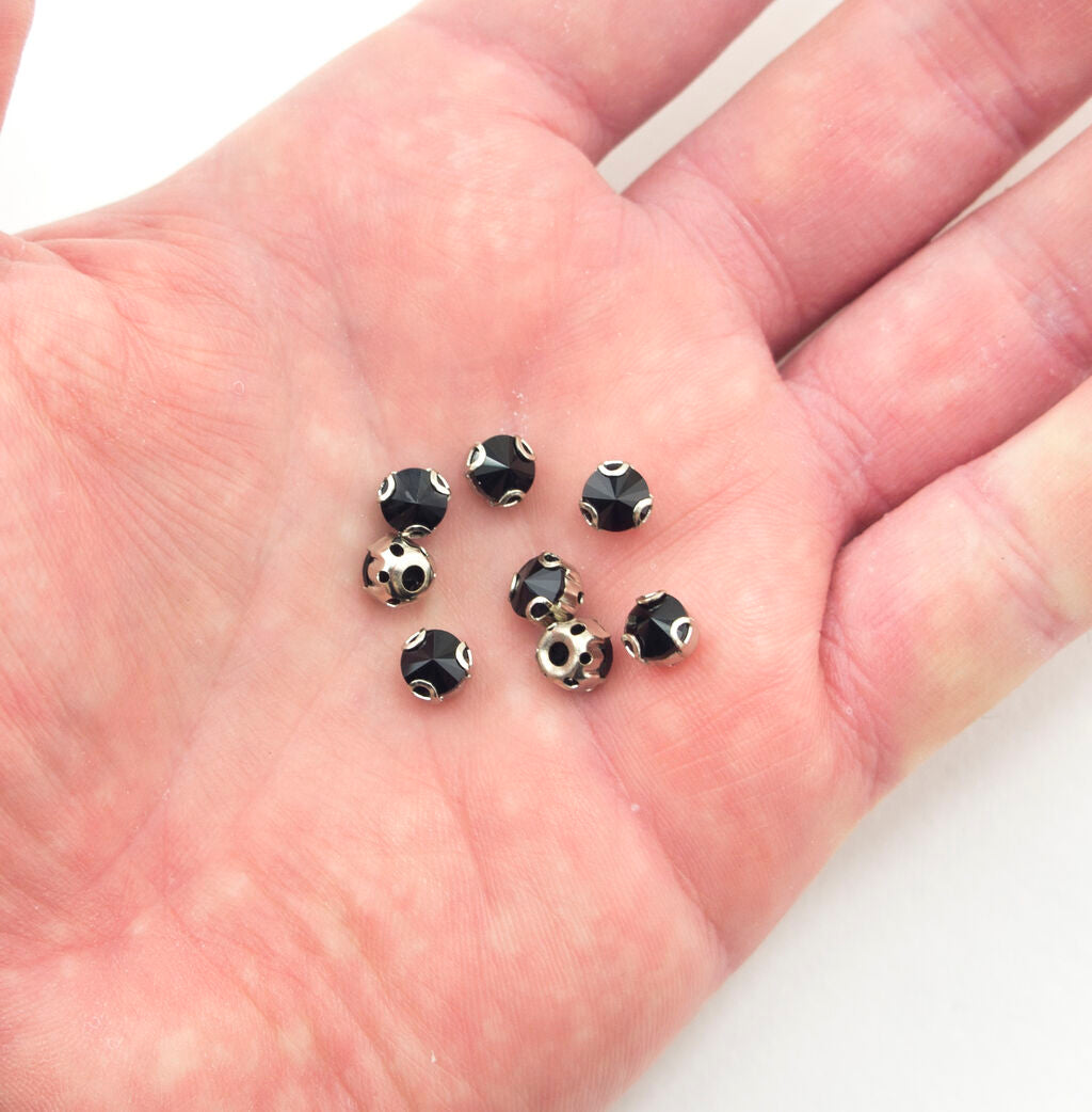 Close-up of a black round crystal sew in trim with metal mount