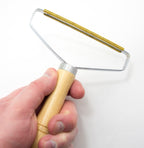 Close-up of a lint remover in use on a fabric surface.