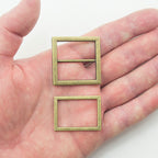 Close-up of two-part antique gold tone metal buckles with measurements.