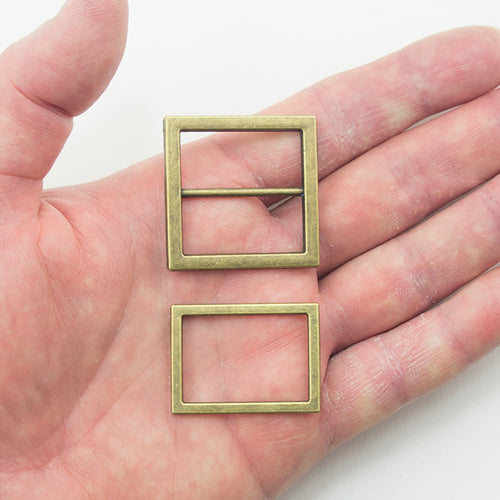 Close-up of two-part antique gold tone metal buckles with measurements.