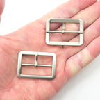 Close-up of a silver tone metal buckle suitable for shoes and bags.