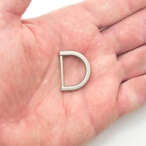 Close-up of a silver tone D ring showing its matt finish.
