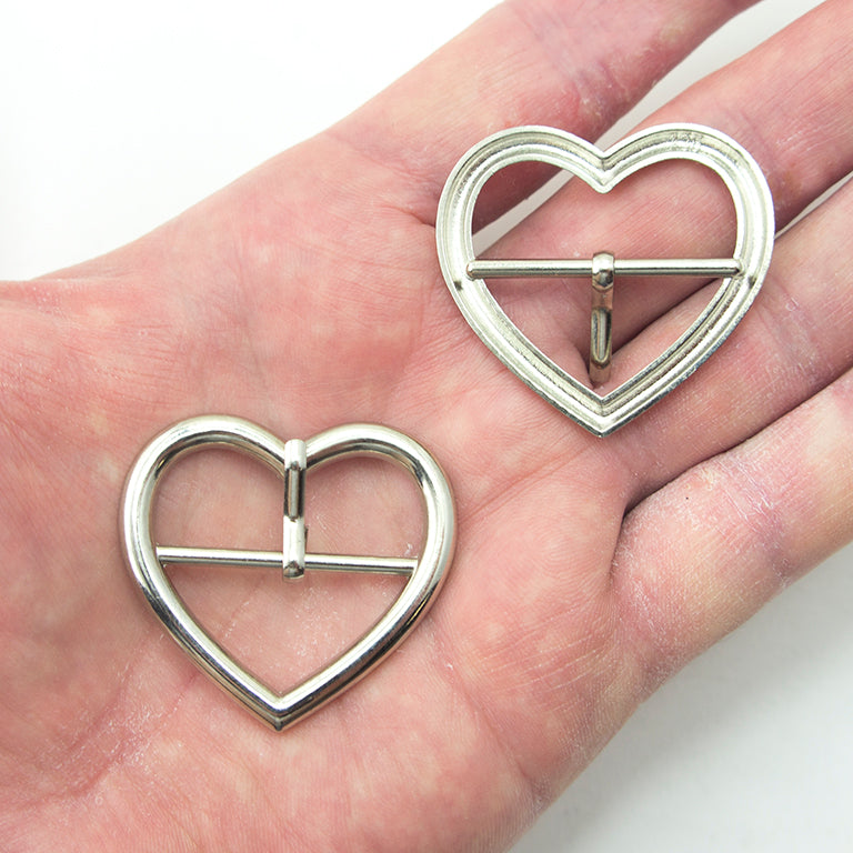 Close-up of a silver tone heart shaped buckle on a strap.