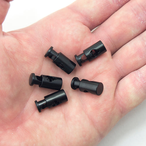 Close-up of a black metal spring stop cord toggle lock showing size and design.