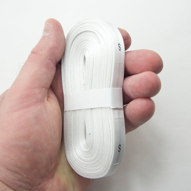 Close-up of white silk size labels on a roll for sewing
