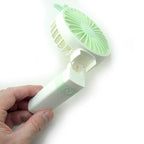 Handheld fan in use, providing relief from summer heat.