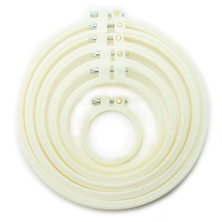 Six cream circular plastic embroidery hoops of various sizes.