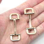 Two gold tone square metal equestrian buckles displayed together.