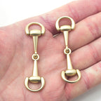 Two matte gold tone metal hinged equestrian buckles displayed together.