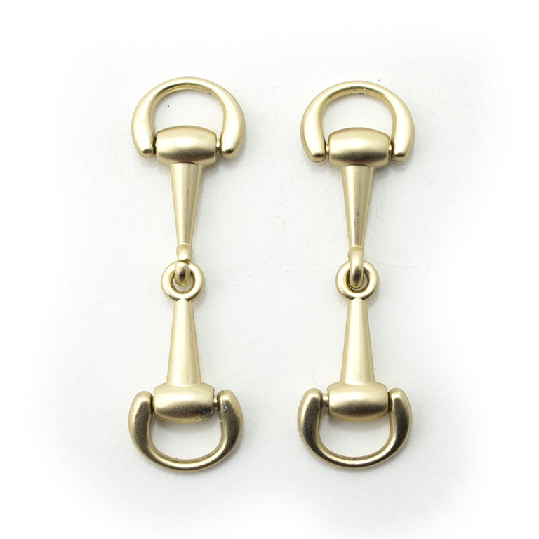 Matte gold tone metal hinged equestrian buckle on a white background.