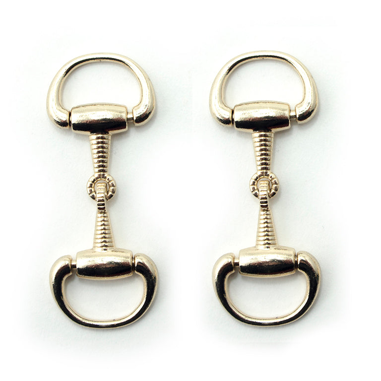 Detailed gold tone metal hinged equestrian buckle on display.
