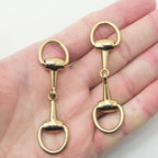 Two darker gold tone metal equestrian buckles displayed together.