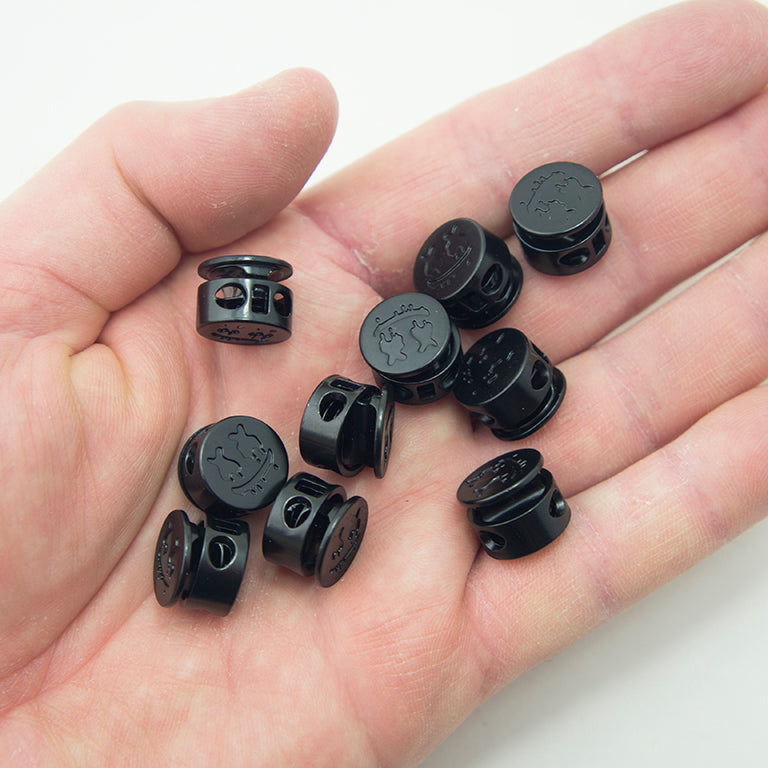 Close-up of a round black metal cord lock with a 5 mm hole