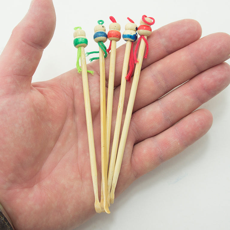 Close-up of a bamboo ear wax remover showing the painted figure design.
