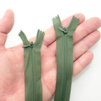 Close-up of an army green invisible zipper showing the metal zip puller.