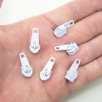 Close-up of a white metal zip pull head attached to a zip.