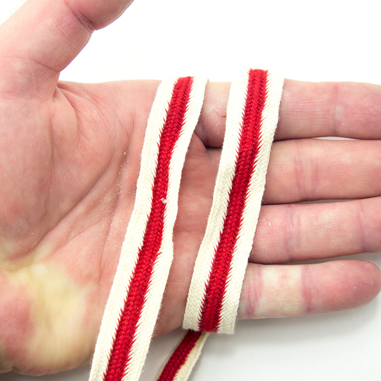 Roll of red cream and navy cotton flat rope with measuring tape.