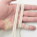 Close-up of cream and red cotton flat rope showing texture.