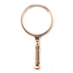 Magnifying glass with rose gold tone handle and 85 mm lens.