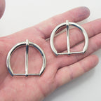 Close-up of a silver tone metal buckle, 48 x 40 mm size.