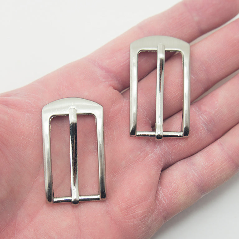 Close-up of a silver tone buckle showing its size and design.
