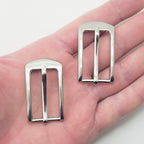Close-up of a silver tone buckle showing its size and design.