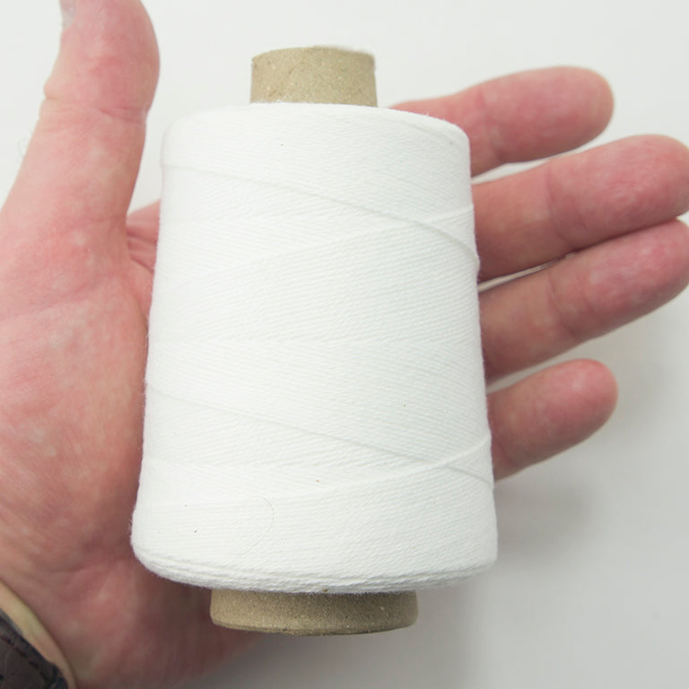 Close-up of a spool of white cotton thread, 1500 ft length.