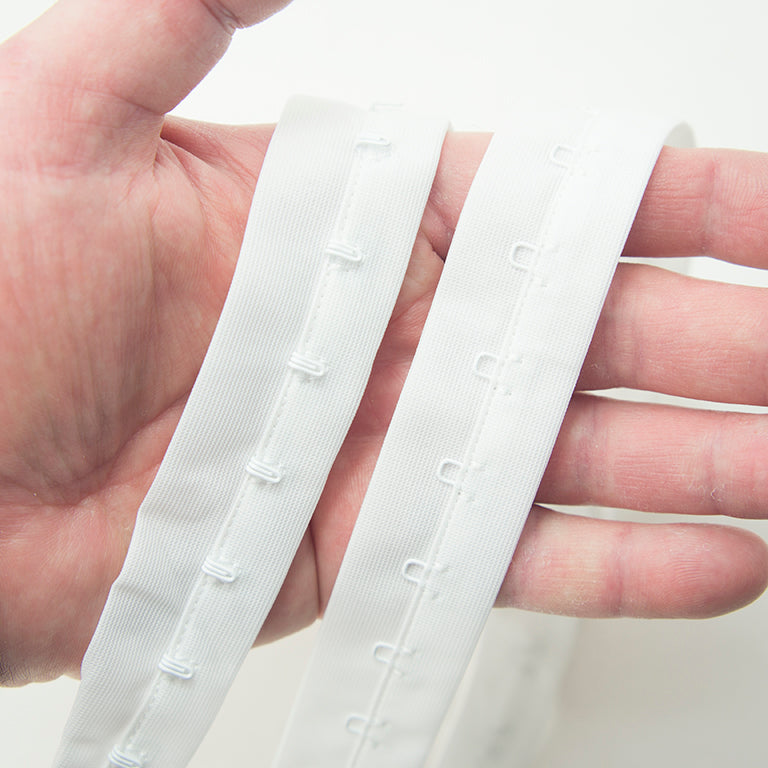 Full length view of 1 metre white bra hook and eye tape on a flat surface.