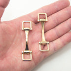 Close-up view of a gold tone metal equestrian buckle showing details.