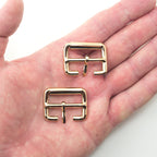 Close-up of a gold tone metal buckle, showing details and dimensions.