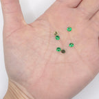 Close-up of a 4mm emerald green 2-hole sew-on rhinestone.