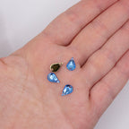 Close-up of a sky blue acrylic teardrop rhinestone showing the flat back and holes.