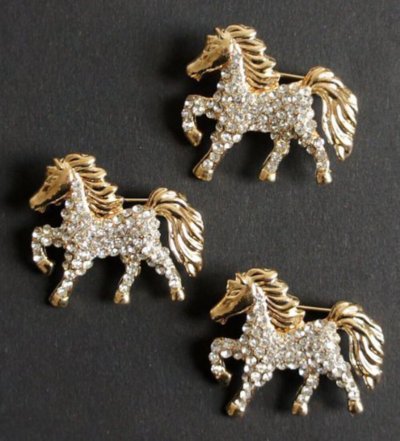 Three elegant clear crystal horse gold brooches displayed together.