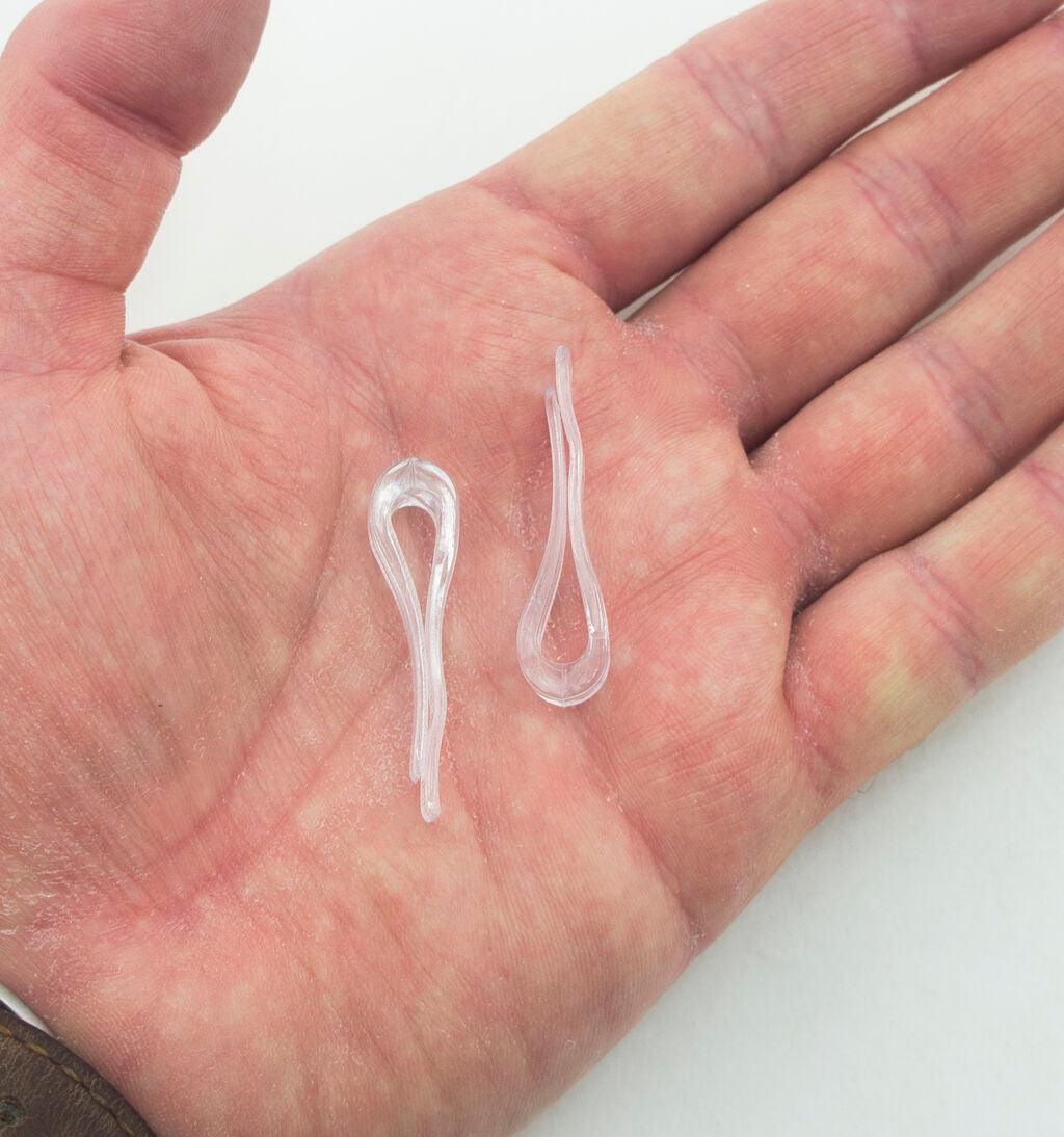 Large plastic garment shirt clips displayed on a fabric background.