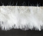 Close-up of white goose feather fringe trim on a roll.