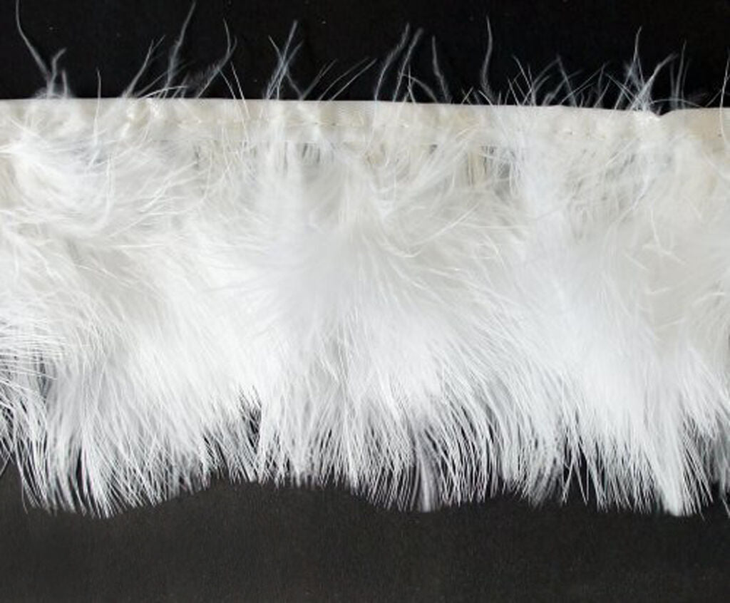 Close-up of white goose feather fringe trim on a roll.