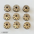 Nine metal bobbins arranged neatly on a white background.