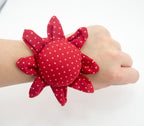 Close-up of red wrist pin cushion showing pin placement